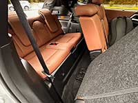 2026-Outlander-PHEV-seating - Kindersley Clarion Cargo area of a car with orange-brown leather rear seats folded down, gray carpeting, and a visible seat belt.
